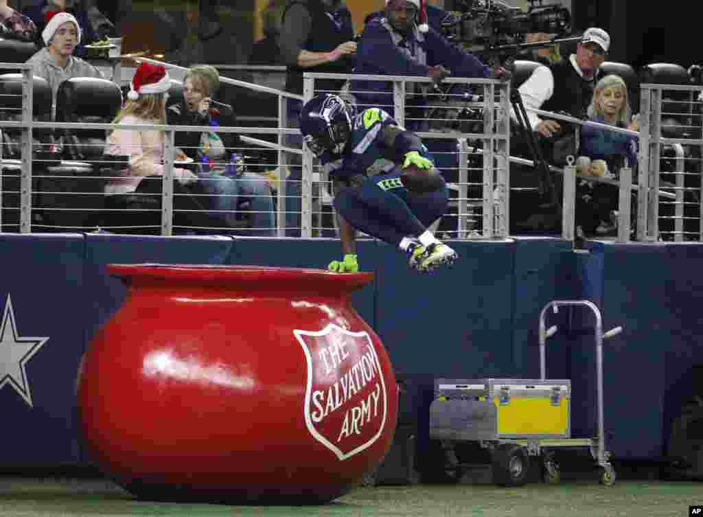 Seattle Seahawks cornerback Justin Coleman (28) leaps into The Salvation Army kettle after returning a Dallas Cowboys' Dak Prescott interception for a touchdown in the second half of an NFL football game, Dec. 24, 2017, in Arlington, Texas.