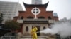 一名工人在武汉汉口教堂救世堂前为防疫新冠病毒喷洒消毒药水。（2020年3月6日）