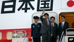 Japanese Prime Minister Shinzo Abe, second from left, waves before his departure for Washington at Haneda International Airport in Tokyo, February 21, 2013.