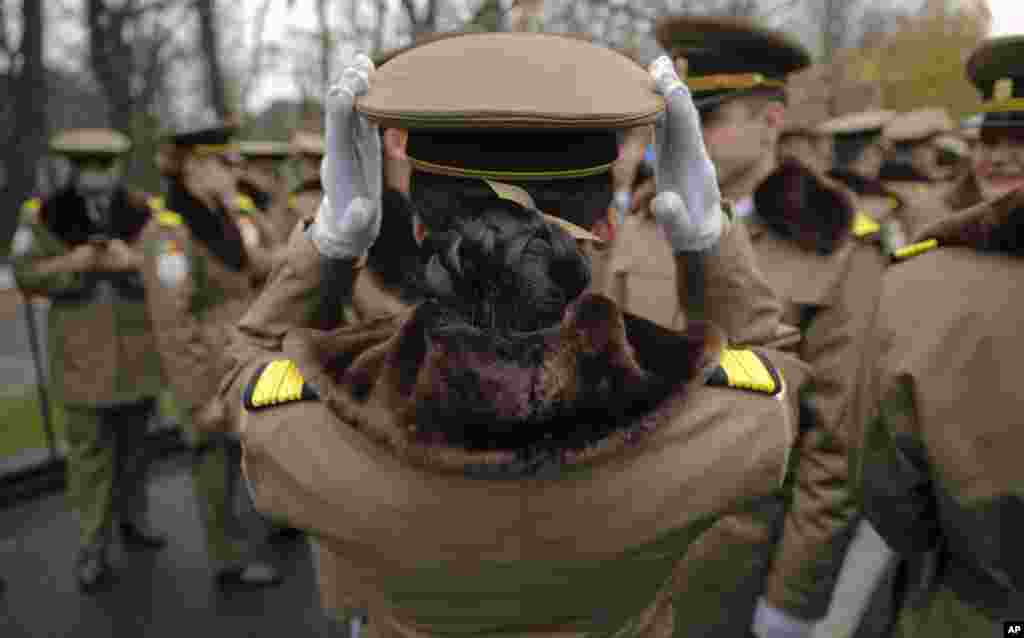 A female member of Romania's military adjusts her hat before taking part in the national day military parade in Bucharest, Romania.