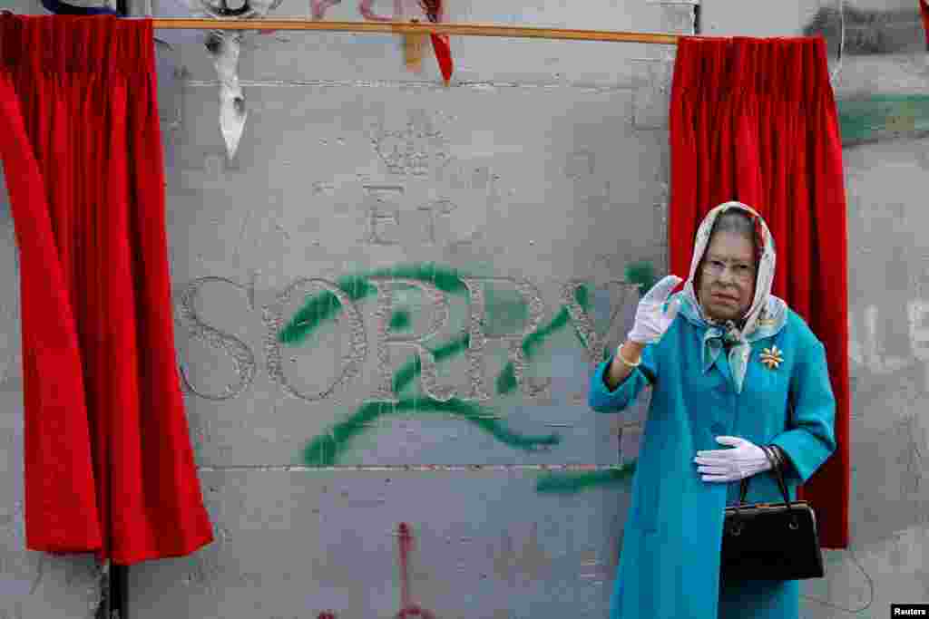 A person, dressed as Britain's Queen Elizabeth II, gestures during an event ahead of the anniversary of the Balfour Declaration, outside Banksy’s Walled Off Hotel in the West Bank city of Bethlehem.