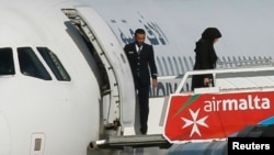 People disembark from a hijacked Libyan Afriqiyah Airways Airbus A320 on the runway at Malta Airport, December 23, 2016.