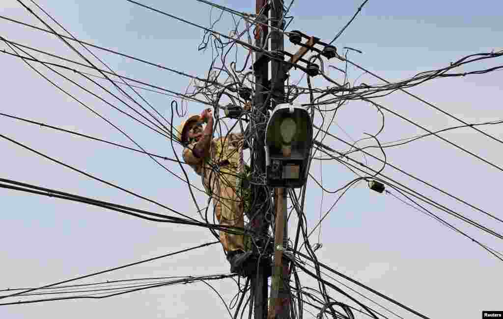 A worker repairs power lines in Kochi, India.