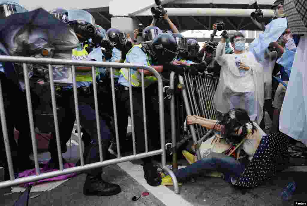 在港府大楼外面，警察与民众发生冲突。一位妇女（右）在和警察的搏斗中躺在地上，紧紧抓住栏杆。 