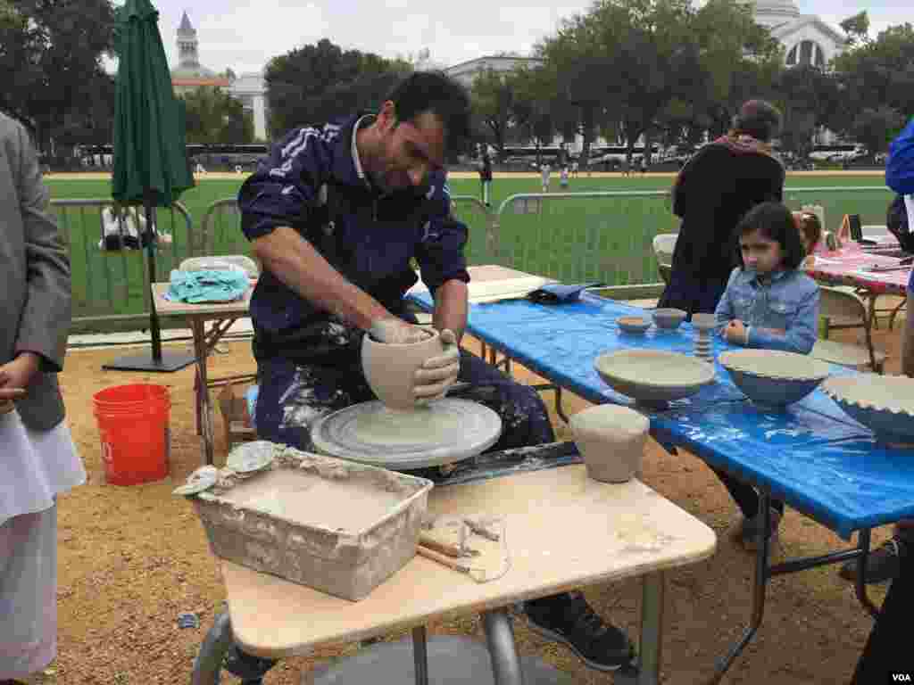 A girl watches ceramicist Abdul Matin Malekzadah demonstrate his craft. (Y. Jung/VOA)
