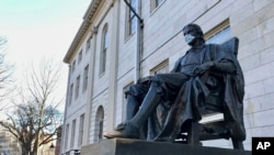 哈佛大学一座地标雕塑，疫情之下有人为它也戴上了口罩。（2020年3月14日）